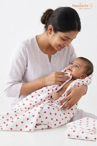 Mother holding a baby wrapped in a Fascinito white blanket with red hearts