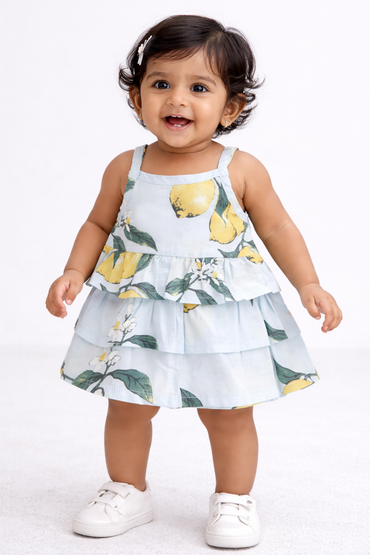 Baby girl wearing a lemon print tiered cotton frock in light blue