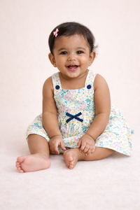 Girl sitting in a floral woven sleeveless cotton frock with front bow detail